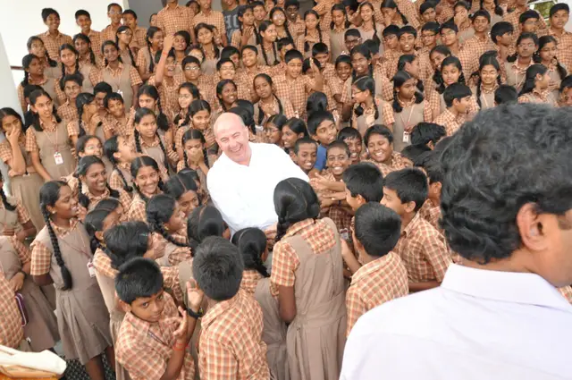 Jeff Hoffman kneeling with schoolchildren in matching polo shirts at a school in India